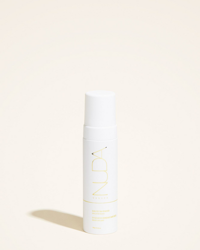 Sunless Tan Remover mousse bottle, featuring a sleek design with white and yellow branding on a neutral background.