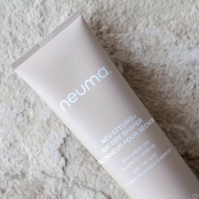Neuma Neu Styling Air-dry Shaper tube with green tea and apricot kernel oil on textured background.