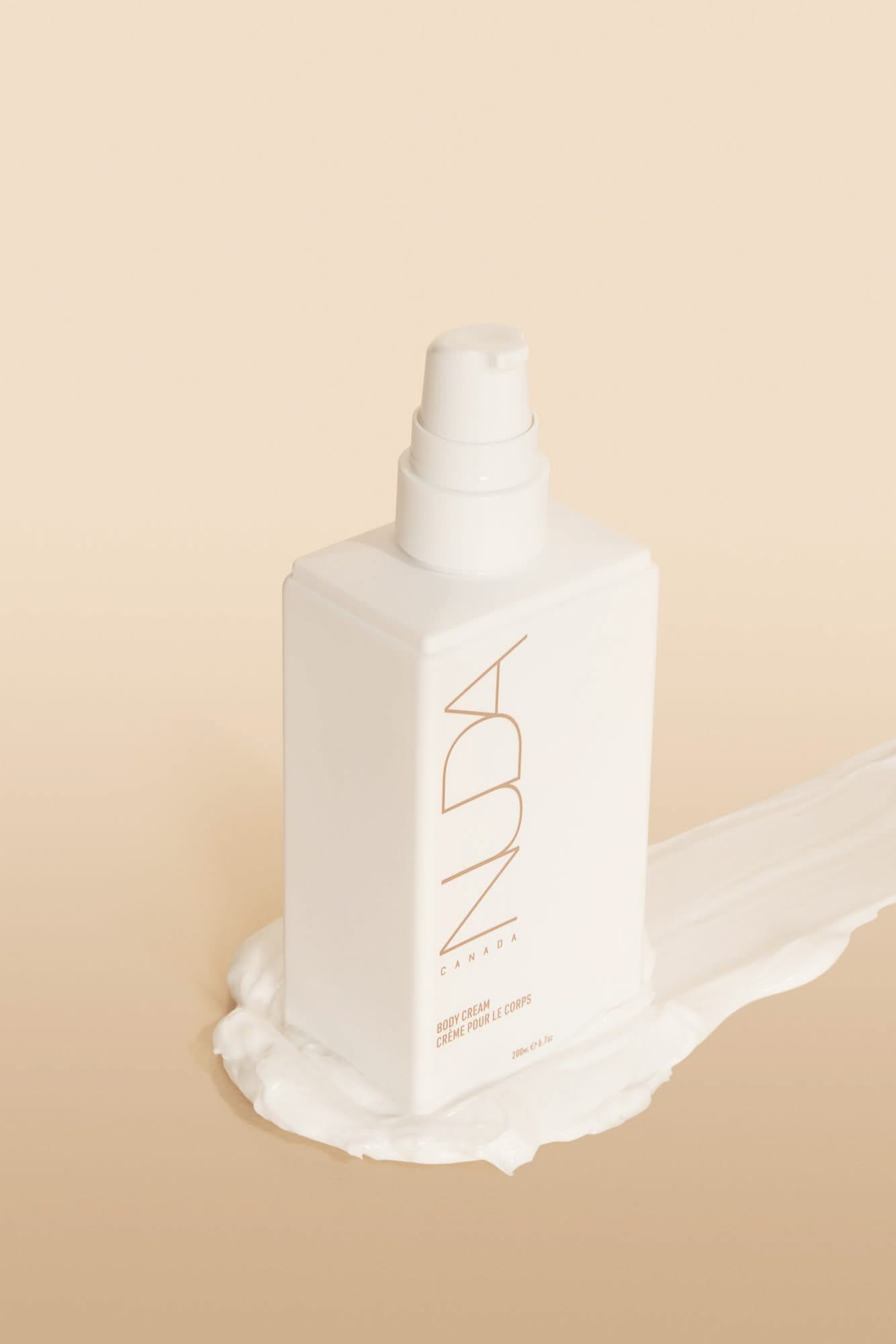 Nuda Routine Kit Body Cream bottle with pump on a creamy backdrop for a radiant tan.