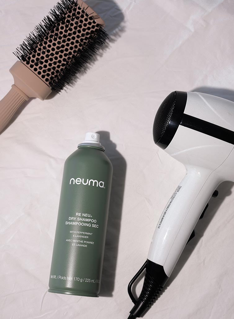 Neuma Re Neu Dry Shampoo with a blow dryer and round brush on a light background, promoting clean and refreshed hair.