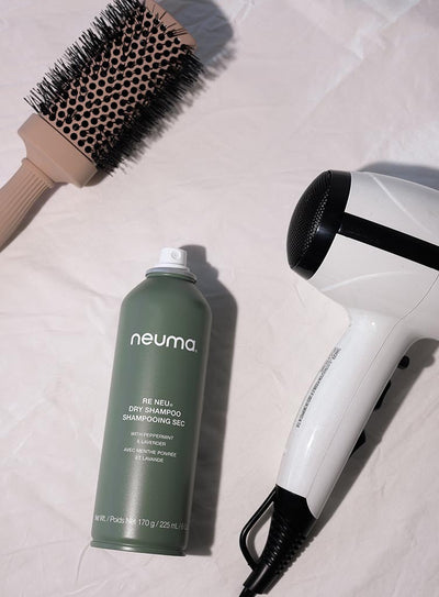 Neuma Re Neu Dry Shampoo with a blow dryer and round brush on a light background, promoting clean and refreshed hair.