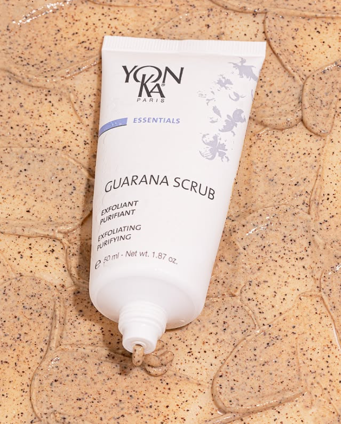 An open bottle of Yonka Guarana Scrub is laying on a table covered in the guarana scrub. 