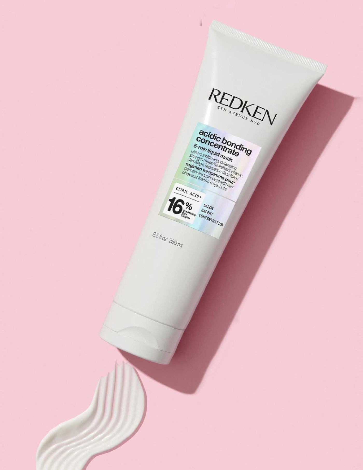 Redken Acidic Bonding Concentrate Liquid Mask in a sleek white tube on a pink background, designed for damaged hair repair.