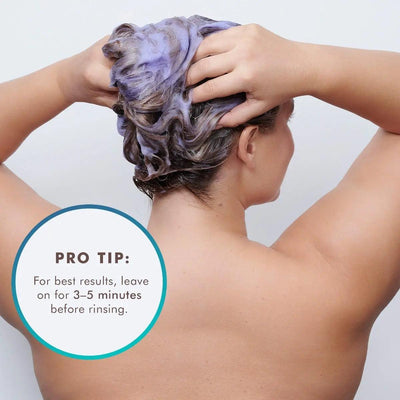 Woman applying Blonde Perfecting Purple Shampoo, highlighting pro tip to leave on for 3-5 minutes before rinsing.