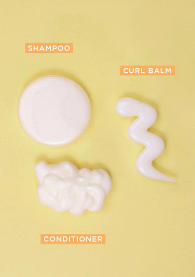 BOUNCE.ME Curl Glitz Kit featuring shampoo, conditioner, and curl balm displayed on a yellow background.