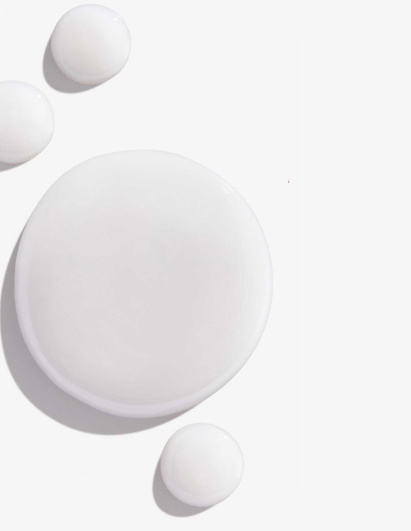 White drops of shampoo representing Redken Color Extend Magnetics Shampoo's creamy texture and formula.