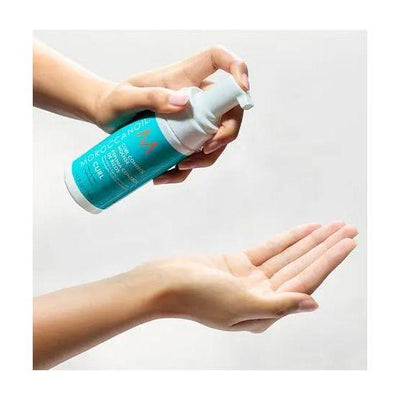 Moroccanoil Curl Control Mousse being dispensed into a hand for defining curls and reducing frizz.