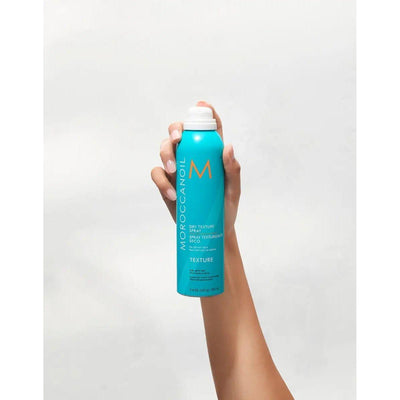 Moroccanoil Dry Texture Spray in a hand, showcasing its argan-oil infused formula for effortless, textured styles.