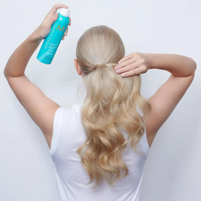 Woman applying Moroccanoil Dry Texture Spray to enhance wavy hair for effortless, textured styles.