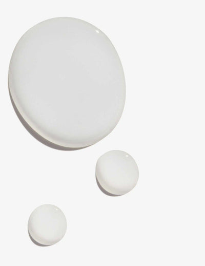 Drops of Redken Extreme Cat Treatment showcasing its creamy texture for hair repair and strengthening.