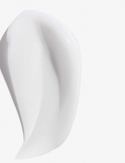 Smooth, white texture of Redken Frizz Dismiss Mask, designed for frizz-free, manageable hair.