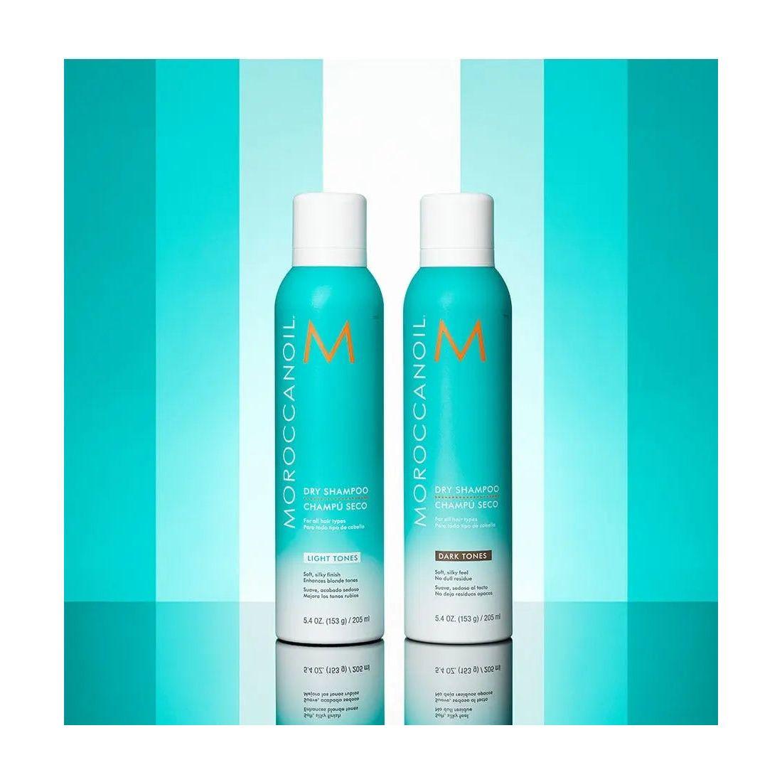 Moroccanoil Dry Shampoo Light Tones bottles against a vibrant turquoise background, showcasing odor removal and brassiness control.