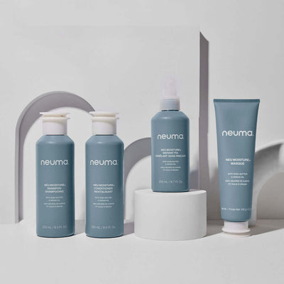 Neuma Moisture hair care products including shampoo, conditioner, and mask displayed on a modern pedestal.