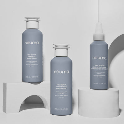 Neuma Repair hair care trio featuring shampoo, conditioner, and leave-in treatment on a minimalist display.
