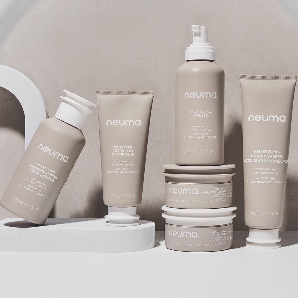 Neuma hair care products displayed on a modern surface, featuring styling clay, texture extender, and air-dry shampoo.