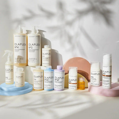Collection of Olaplex hair care products including Nº.4 Bond Maintenance Shampoo and Nº.5 conditioner on colorful stands.