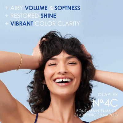 Cheerful woman showcasing healthy, voluminous hair after using Olaplex No. 4C Bond Maintenance Clarifying Shampoo.