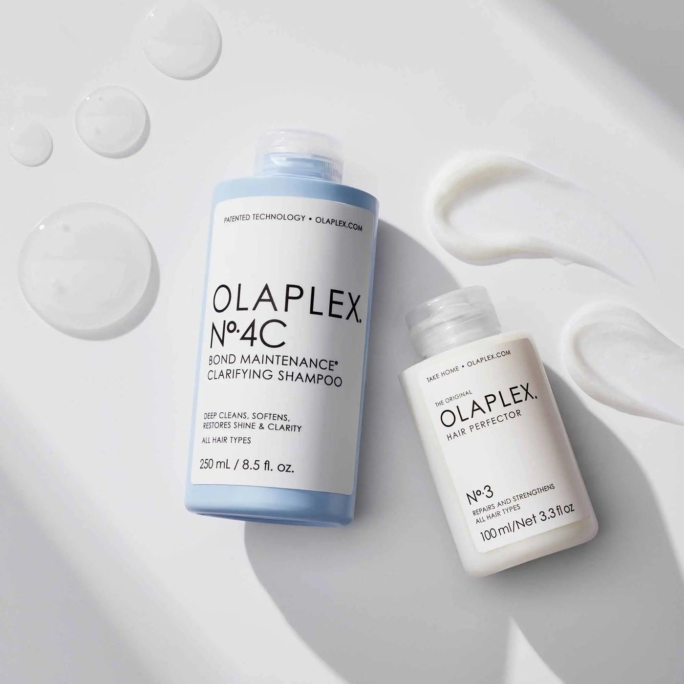 Olaplex No. 4C Bond Maintenance Clarifying Shampoo and No. 3 Hair Perfector bottles with shampoo textures. Ideal for all hair types.