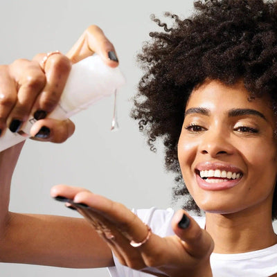 Woman applying Olaplex No.9 Bond Protector Nourishing Hair Serum for shiny, healthy hair.