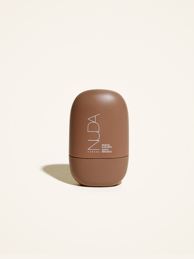 Nuda Bronzing Glow Drops in a sleek brown container on a light background, perfect for achieving a sun-kissed glow.