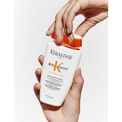 Kérastase Nutritive Bain Satin Riche shampoo bottle being opened, designed for very dry hair nourishment.