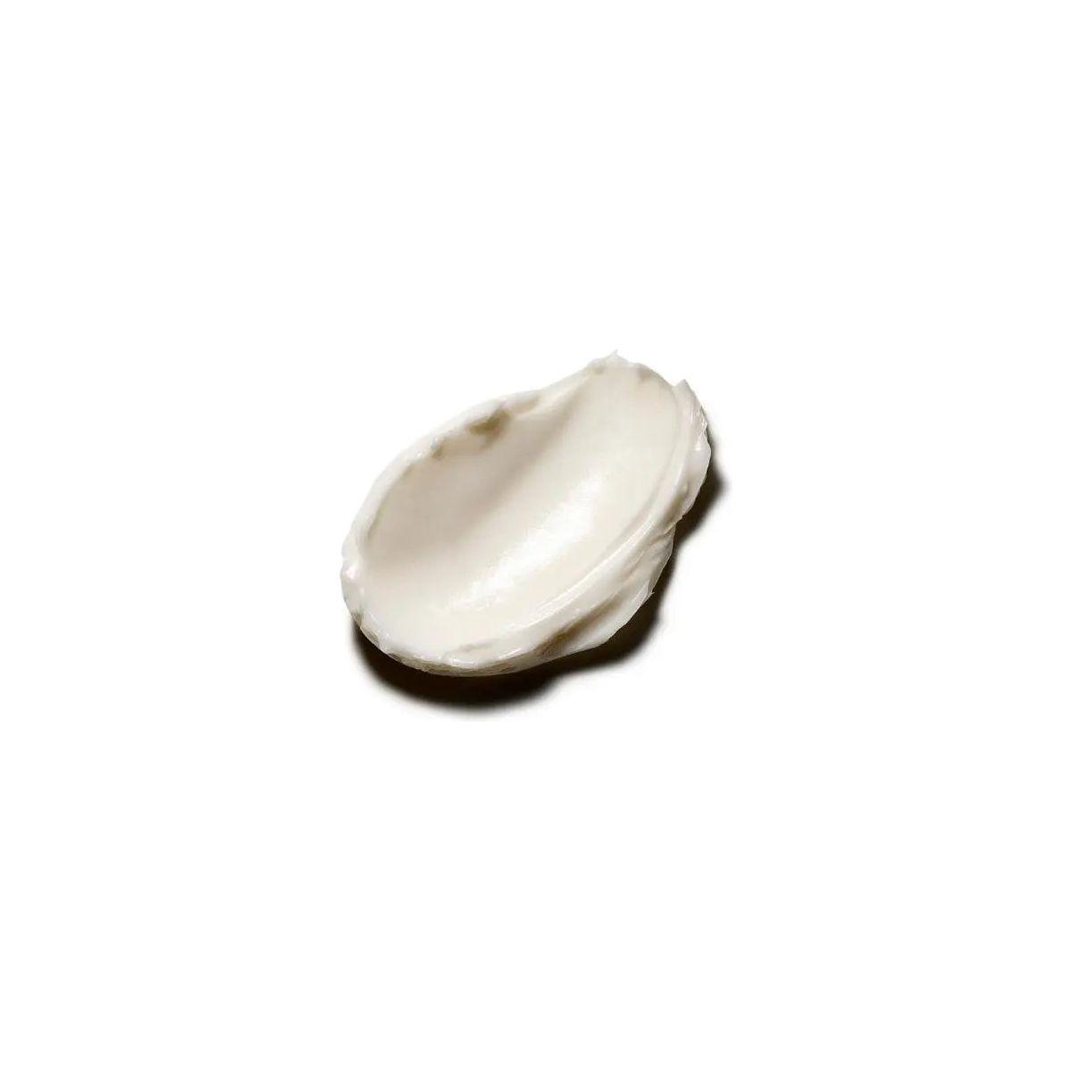 Smooth, creamy texture of Original Body Butter lotion on a spoon, showcasing its rich, moisturizing formula.