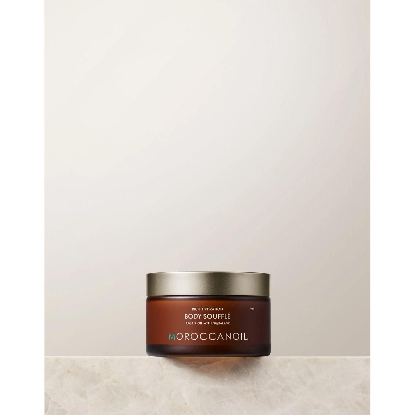 Original Body Soufflé by Moroccanoil in a jar on a marble surface, showcasing a lightweight whipped moisturizer for hydration.