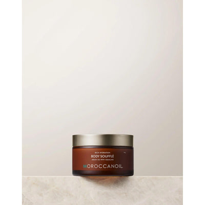 Original Body Soufflé by Moroccanoil in a jar on a marble surface, showcasing a lightweight whipped moisturizer for hydration.