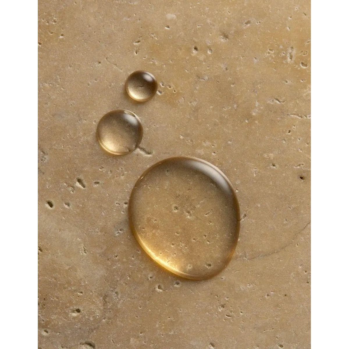Drops of nourishing oil on a textured surface, highlighting the hydrating ingredients of Originale Fragrance Hand Wash.