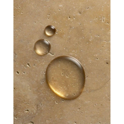 Drops of nourishing oil on a textured surface, highlighting the hydrating ingredients of Originale Fragrance Hand Wash.