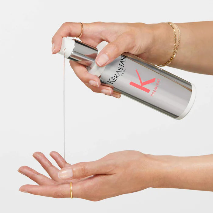 Hand pouring Kerastase Concentré Ultra-Réparateur hair treatment for damaged hair from a bottle.
