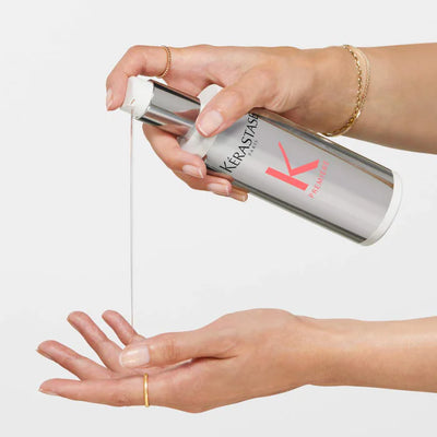 Hand pouring Kerastase Concentré Ultra-Réparateur hair treatment for damaged hair from a bottle.