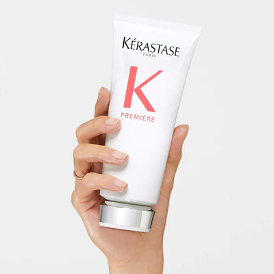 Kérastase Fondant Fluidité Réparateur Conditioner held in hand, showcasing its sleek design and packaging.