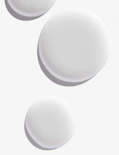 White round droplets of Scalp Relief Dandruff Shampoo on a light background, showcasing its smooth texture.