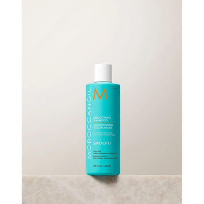 Moroccanoil Smoothing Shampoo bottle on a marble surface, designed for frizzy hair control and hydration.