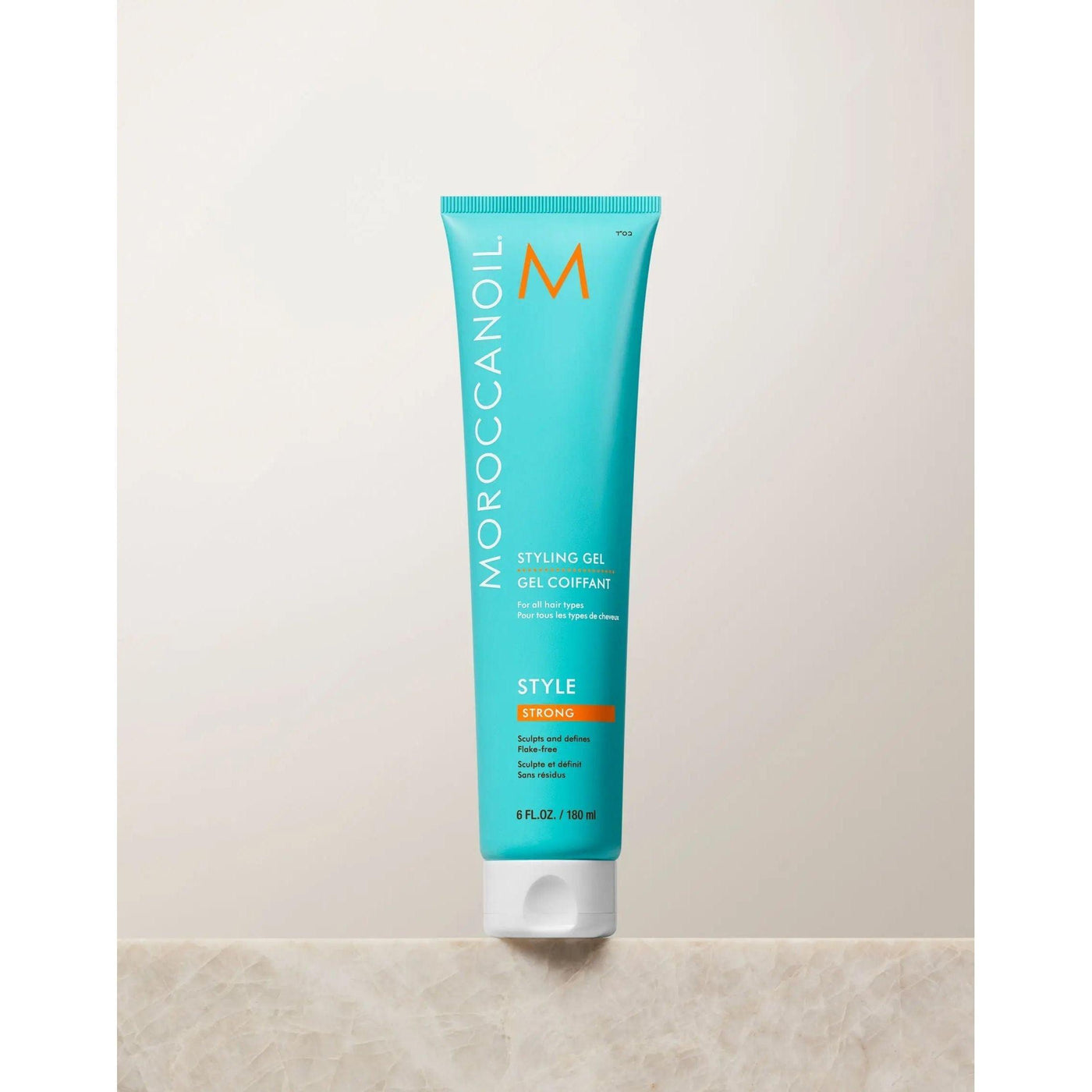 Moroccanoil Strong Hold Styling Gel in turquoise tube on a countertop, perfect for sleek, hydrated hairstyles.