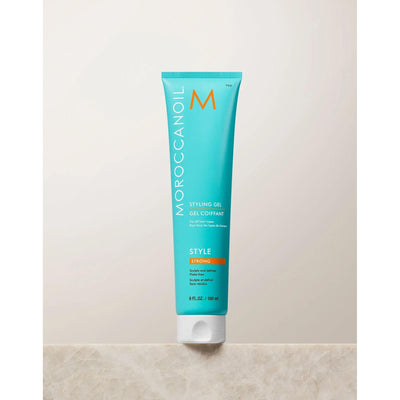 Moroccanoil Strong Hold Styling Gel in turquoise tube on a countertop, perfect for sleek, hydrated hairstyles.