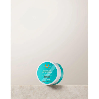 Moroccanoil Texture Clay in a round container, perfect for sculpting hair with a matte finish and strong hold.
