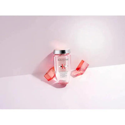 Kerastase hair product bottle with pink geometric shapes behind on white background