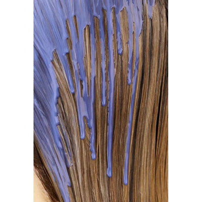 Purple hair dye being applied on long brown hair for vibrant color transformation.