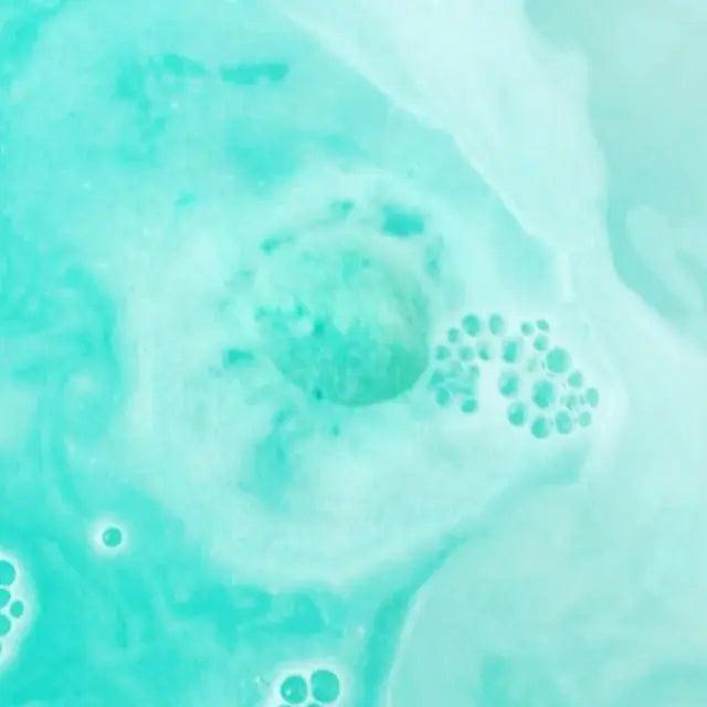 Calypso bath bomb dissolving in a turquoise bath with bubbles, showcasing aloe and cucumber scent.