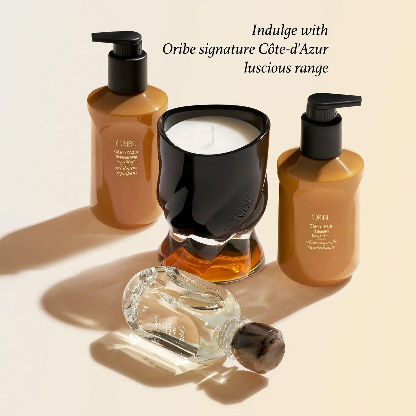 Oribe Côte d'Azur scented candle surrounded by luxurious hair and body products, evoking the South of France.