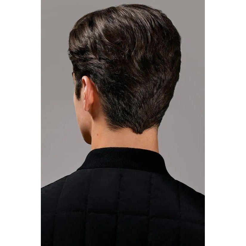 Back view of man with stylish short dark hair, wearing a black quilted jacket.