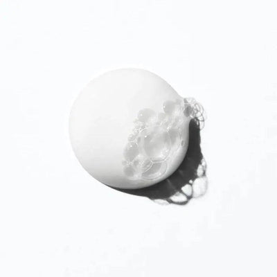 White creamy shampoo with bubbles on a light background, representing gentle hydration for curly hair.