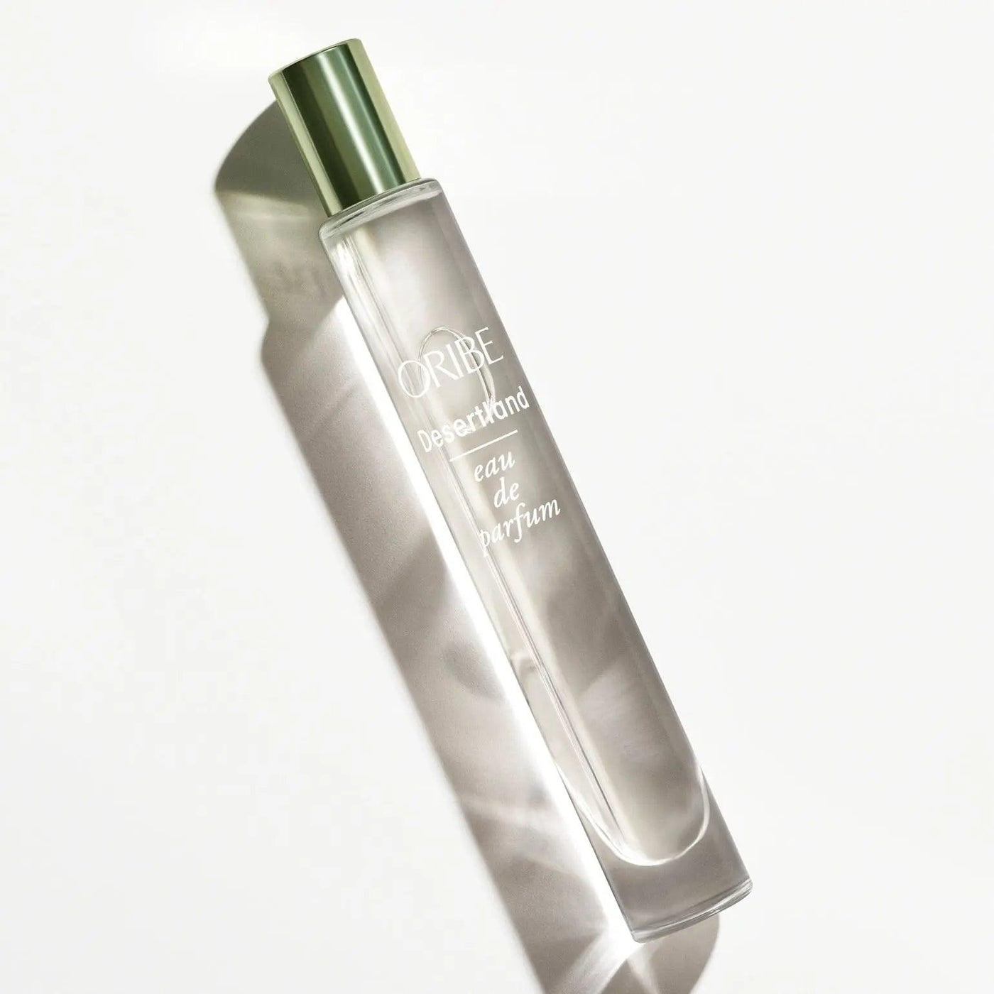 Oribe Desertland Eau De Parfum bottle showcasing elegant design with green cap and reflective surface.