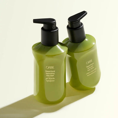 Two bottles of Oribe Desertland Replenishing Body Wash on a light background, showcasing luxurious green packaging.