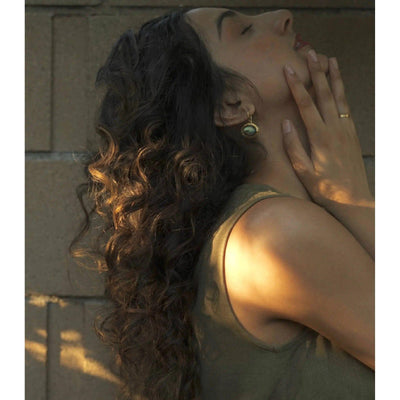 Woman with defined braided curls, showcasing healthy shine and bounce in natural light.