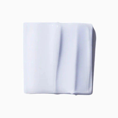 Close-up of white skincare cream texture on a square surface, illustrating smooth and rich consistency.