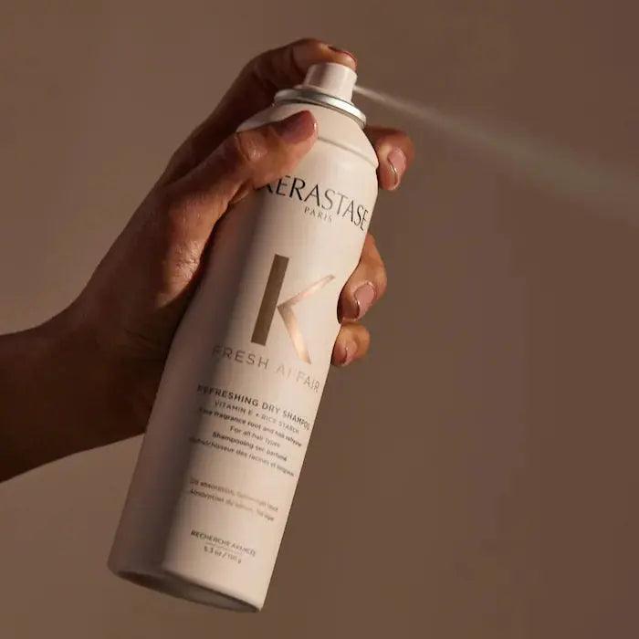 Hand holding Kérastase Paris dry shampoo spray bottle for hair freshness and volume