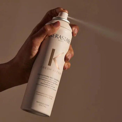 Hand holding Kérastase Paris dry shampoo spray bottle for hair freshness and volume